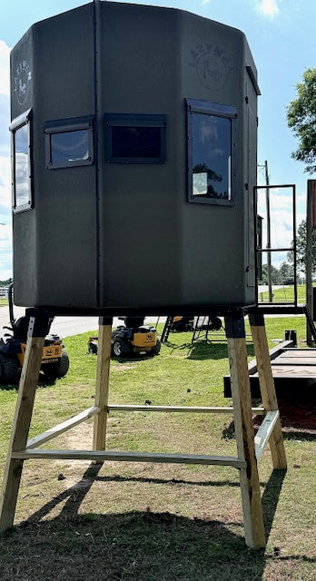 Hunter's stand on a grassy field with a clear sky